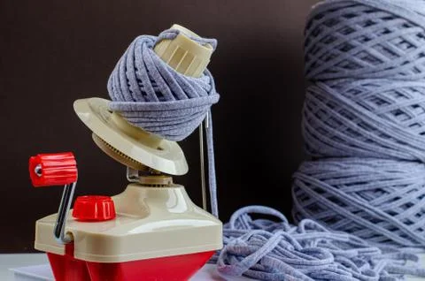 Hand plastic wool winder at work, gray yarn balls, brown background. prepair  Stock Photos