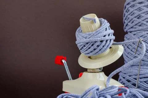 Hand plastic wool winder at work, gray yarn balls, brown background. prepair  Stock Photos