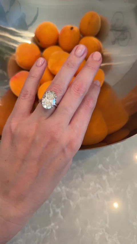 Hand with platinum engagement ring brushing apricots on marble vertical video Stock Footage 317021975