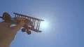 The hand play with a wooden plane on the background of a bright sun 4k or 4k+ Resolution