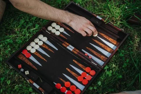 Hand playing backgammon on a grass-covered outdoor setting Stock Photos
