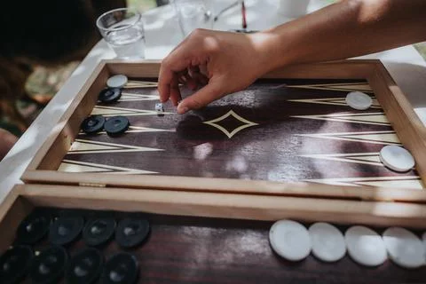 Hand playing backgammon in an outdoor setting with sunlight Stock Photos