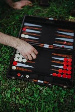 Hand playing backgammon outdoors on grass with dice and pieces Stock Photos