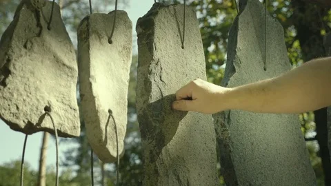Hand plays on sounding stones. Stones hung on string like musical drumming tool. Stock Footage
