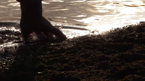Hand plays with water at sunset Stock Footage 153612580