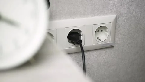 Hand plug black mobile charger adapter into the wall power socket close-up view Stock Footage 163644273