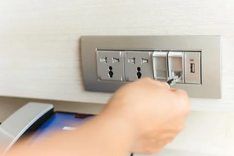 Hand plug in internet cable wire into extender device socket on the wall. Foto stock