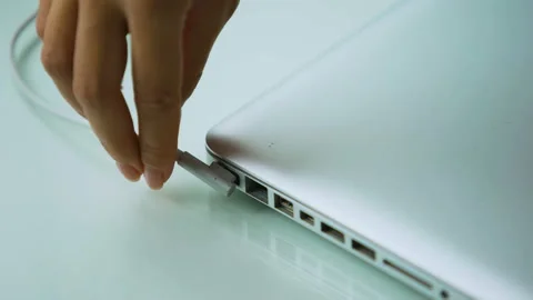 Hand plugging adapter in laptop computer, recharging pc after day of working Stock Footage 98816855