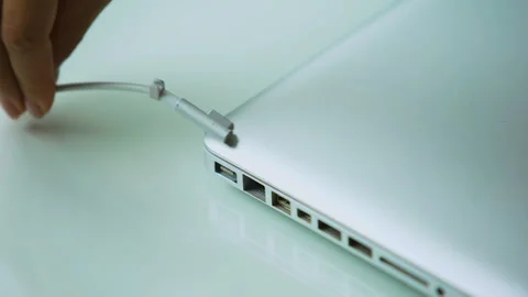 Hand plugging adapter in laptop computer, recharging pc after day of working Stock Footage 98822808