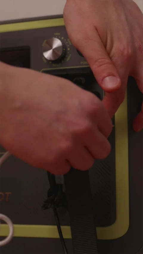 Hand plugging additional USB cable into loaded portable power station Stock Footage 347068994