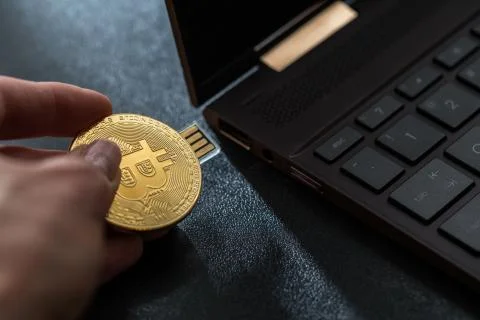 A hand plugging in a Bitcoin thumb drive into windows laptop Stock Photos