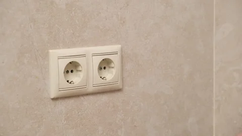 Hand plugging a black electrical plug into a white wall socket. Close-up Stock Footage 291846847