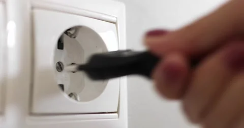 Hand plugging black power plug into white multiple socket indoors. Stock Footage 156792209