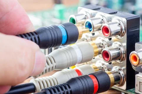 Hand plugging a blue RCA cable into an analog audio-video connector panel on  Foto stock