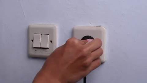 Hand plugging the cable into a electrical outlet Stock Footage 271216966