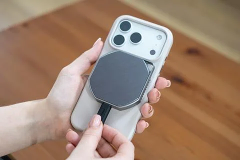 A hand plugging a cable into an external magnetic SSD attached to a modern Stock Photos