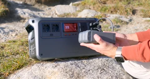 Hand Plugging Cable Into Portable Power Station Charging Drone Batteries Stock Footage 323081455