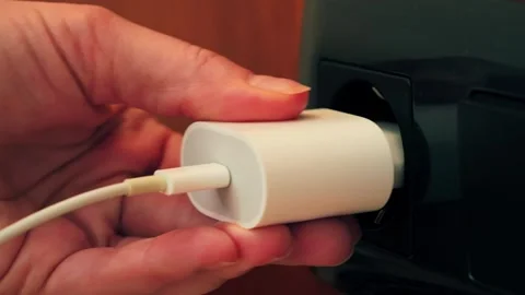 Hand plugging charger into power outlet, close-up of electricity usage and Video stock 334134433