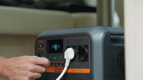 Hand Plugging Electric Cable into Power Booster While Camping Off Grid in Camper Stock Footage 328830877