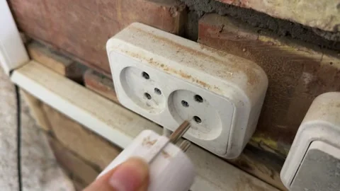 Hand plugging electrical cord into wall socket, home power connection concept, Stock Footage 337121608