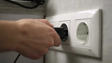 Hand plugging electronic charger adapter into electric wall socket Stock Footage 163644949