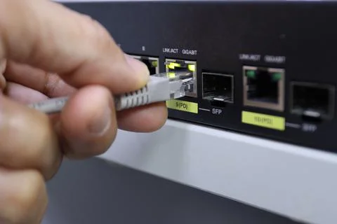 Hand plugging an Ethernet cable into a network switch port technology Stock Photos