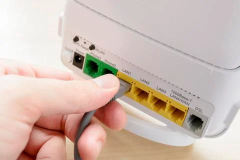 Hand Plugging an Ethernet Cable Into a Wifi Router Port Foto stock