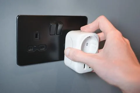 Hand Plugging EU Adapter Into British Power Socket, Travel Foto stock