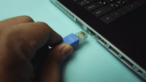 Hand plugging in internet cable to the laptop Stock Footage