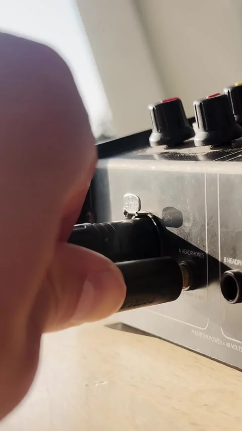 Hand plugging a jack headphone cable into an audio intercom unit, showing sound Stock Footage 337228889