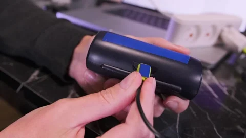 Hand plugging micro USB cable into wireless headphones charging case, close-up Stock Footage 333650031