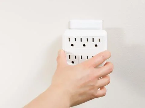 Hand plugging in multiple electrical unit into wall outlet Stock Photos