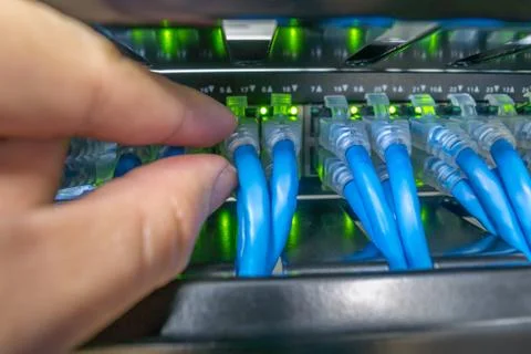 Hand plugging Network switch and ethernet cables connected in rack cabinet Stock Photos