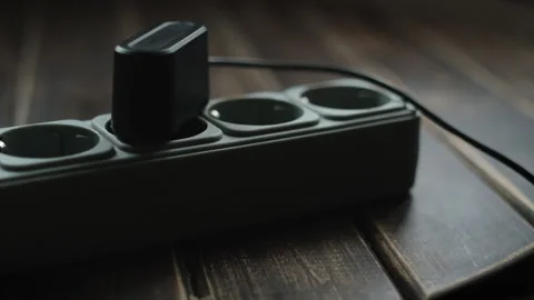 Hand plugging phone charger into extension cord Stock Footage 327907888