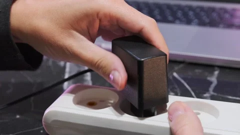 Hand plugging power adapter into extension cord socket, close-up of connecting 스톡 동영상 333649736