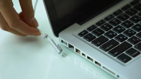 Hand plugging power adapter in laptop, everyday computer technology personal use Stock Footage 98820889