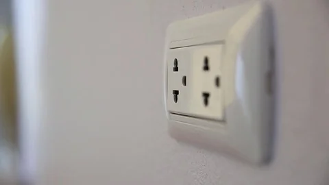 Hand plugging in a power cord and then unplugging it in a typical electrical out Stock Footage 78557675