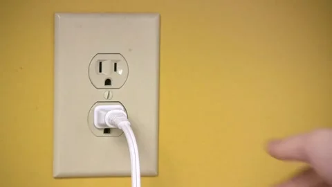 Hand Plugging a Power Cord into Wall Outlet on Yellow Background Stock Footage 314303406