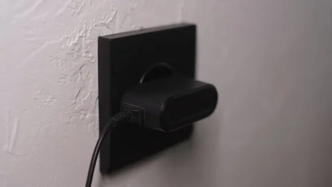 Hand plugging smartphone charger into power socket Stock Footage 327907896