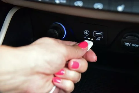 Hand plugging USB cable into the USB port on the car dashboard Stock Photos
