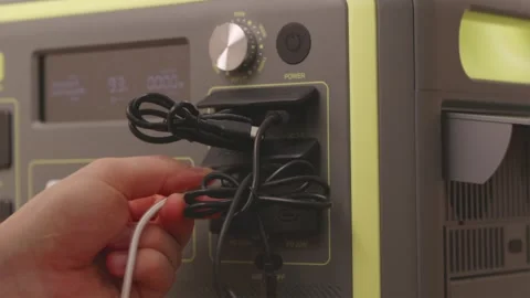 Hand plugging USB charging cable into portable power station port Stock-Footage 347068993