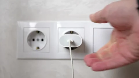 Hand plugging white charger into wall socket Stock Footage 316591301