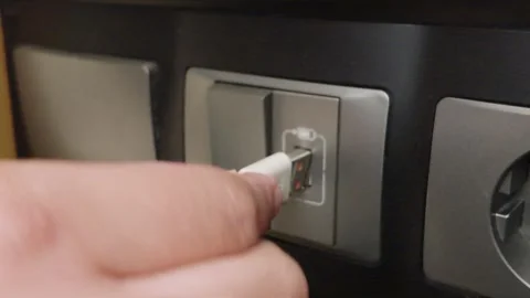Hand plugging white charging cable into power outlet socket panel. 動画素材 344092329