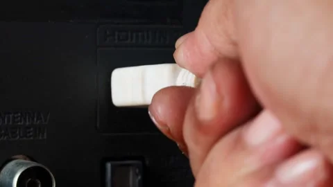 Hand plugging a white HDMI cable into an HDMI port on the back of a television. Stock Footage 344918040