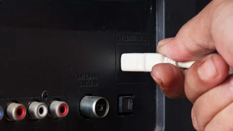 Hand plugging a white HDMI cable into an HDMI port on the back of a television. Stock Footage 344918041