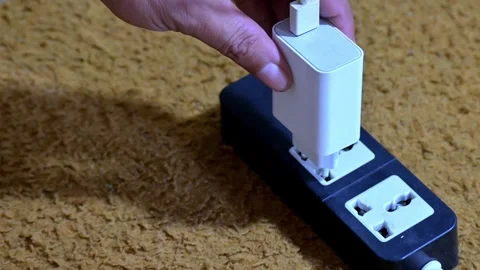 Hand plugging white USB power adapter into black multi outlet power strip Stock Footage 328787940
