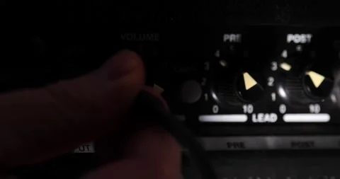 Hand Plugging the wire into the amplifier turning volume up Video stock 204901365