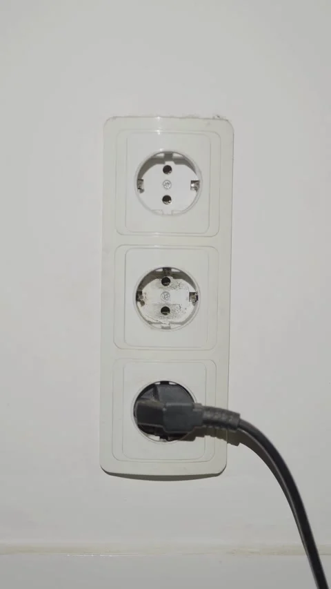 A hand plugs a black power cable into a socket Stock Footage 333527143