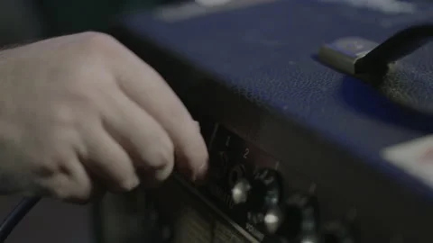 Hand plugs cable into an amplifier and makes adjustments to various knobs on amp 스톡 동영상 202900382