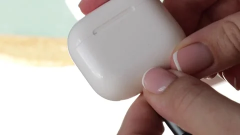 A hand plugs a charging cable into a white case for wireless earbuds, initi.. Stock Footage 320738439